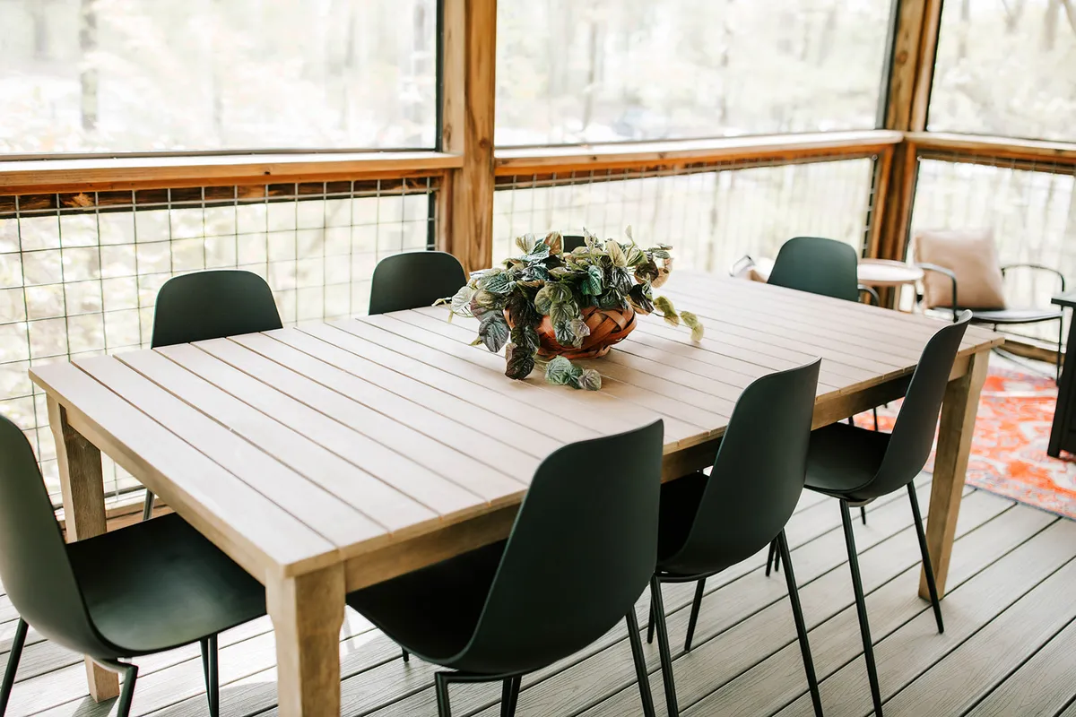 A sunlit dining area with a table, potted plant, and chairs, creating a relaxed ambiance ideal for shared meals, conversations, or pre-event preparations.