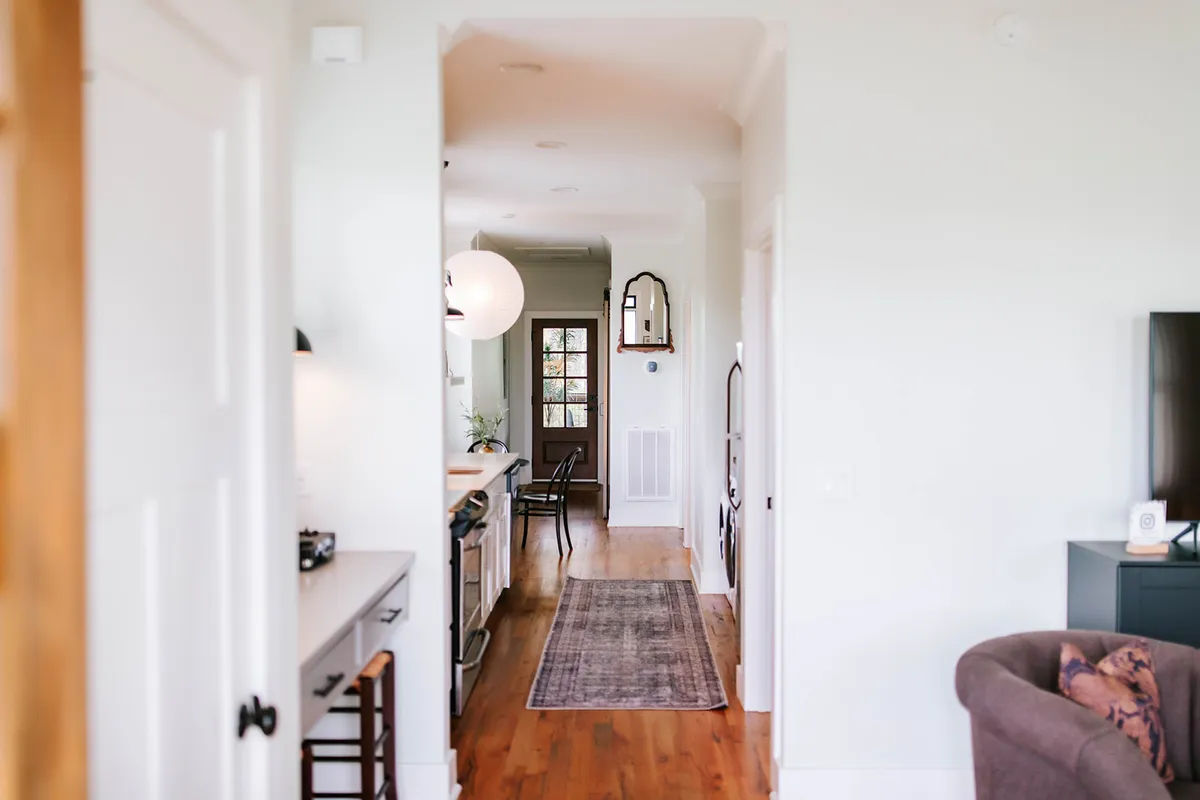 A long, welcoming hallway leads to a sunlit kitchen area, inviting guests into the heart of the cabin where socializing and relaxation happen. The open layout hints at togetherness and ease of movement.