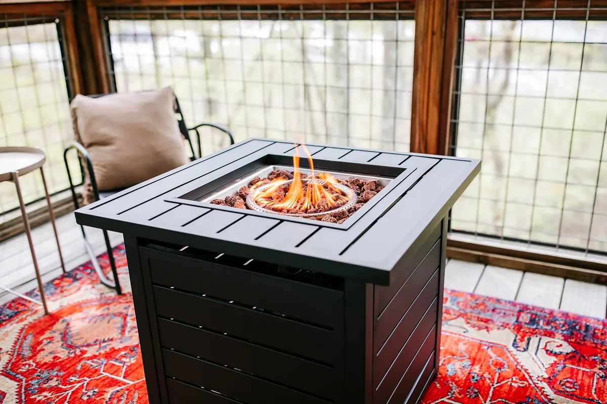 A cozy interior scene arranged around a fire pit, with colorful rugs and comfortable chairs suggesting a relaxing gathering space for families and friends to unwind after a day out.