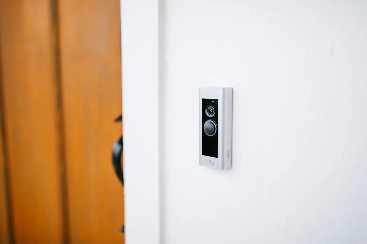 This image depicts a welcoming wooden door with a doorbell camera, providing the first impression as guests arrive at the cottage. The mood is secure and inviting, promising both privacy and peace of mind.