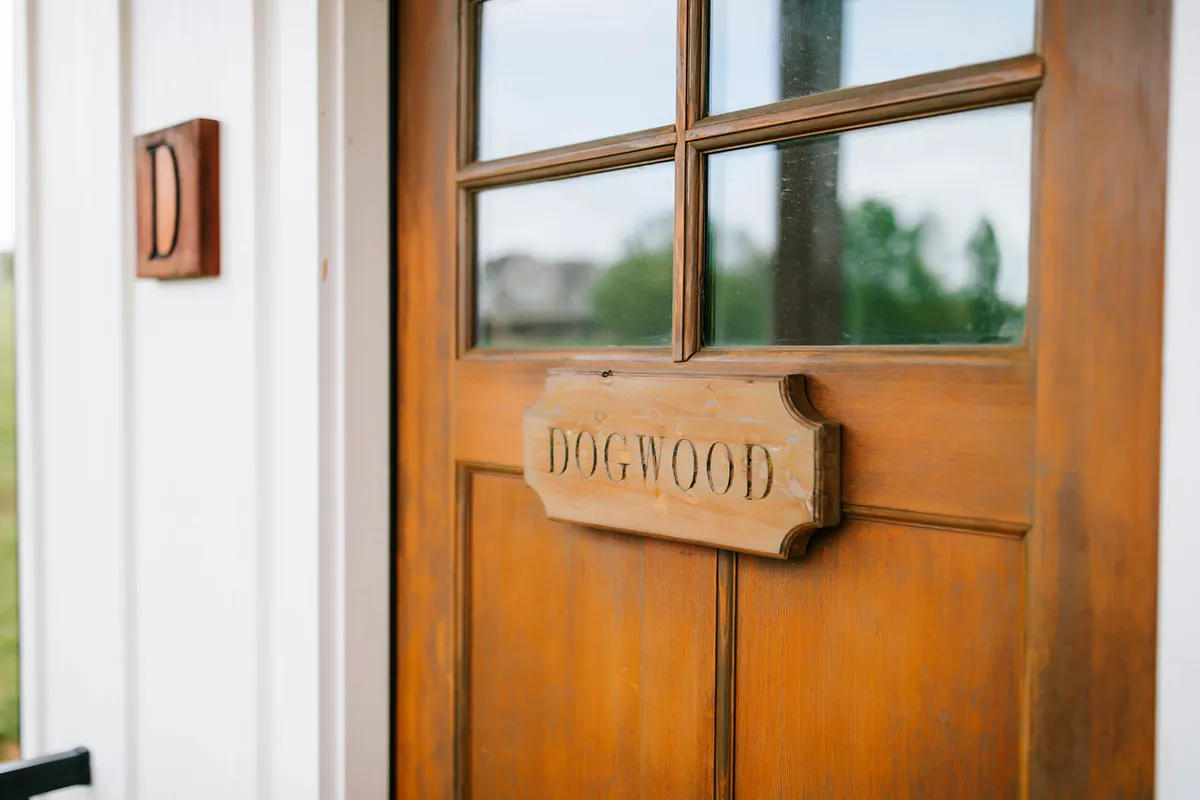 This image captures the cabin's entrance, featuring a wooden door with a name plaque and surrounding glass panels. The mood is warm and inviting, suggesting the start and end of each day's adventure.